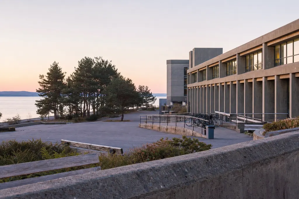 Campus universitar modern lângă mare, în lumina dimineții, cu clădiri de beton și pini (imagine generată cu AI)